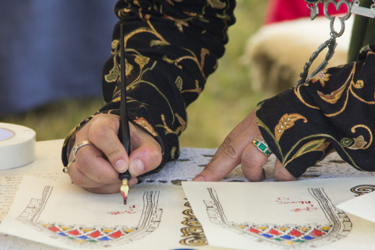 Fountain pen in hand, writing script on illuminated paper